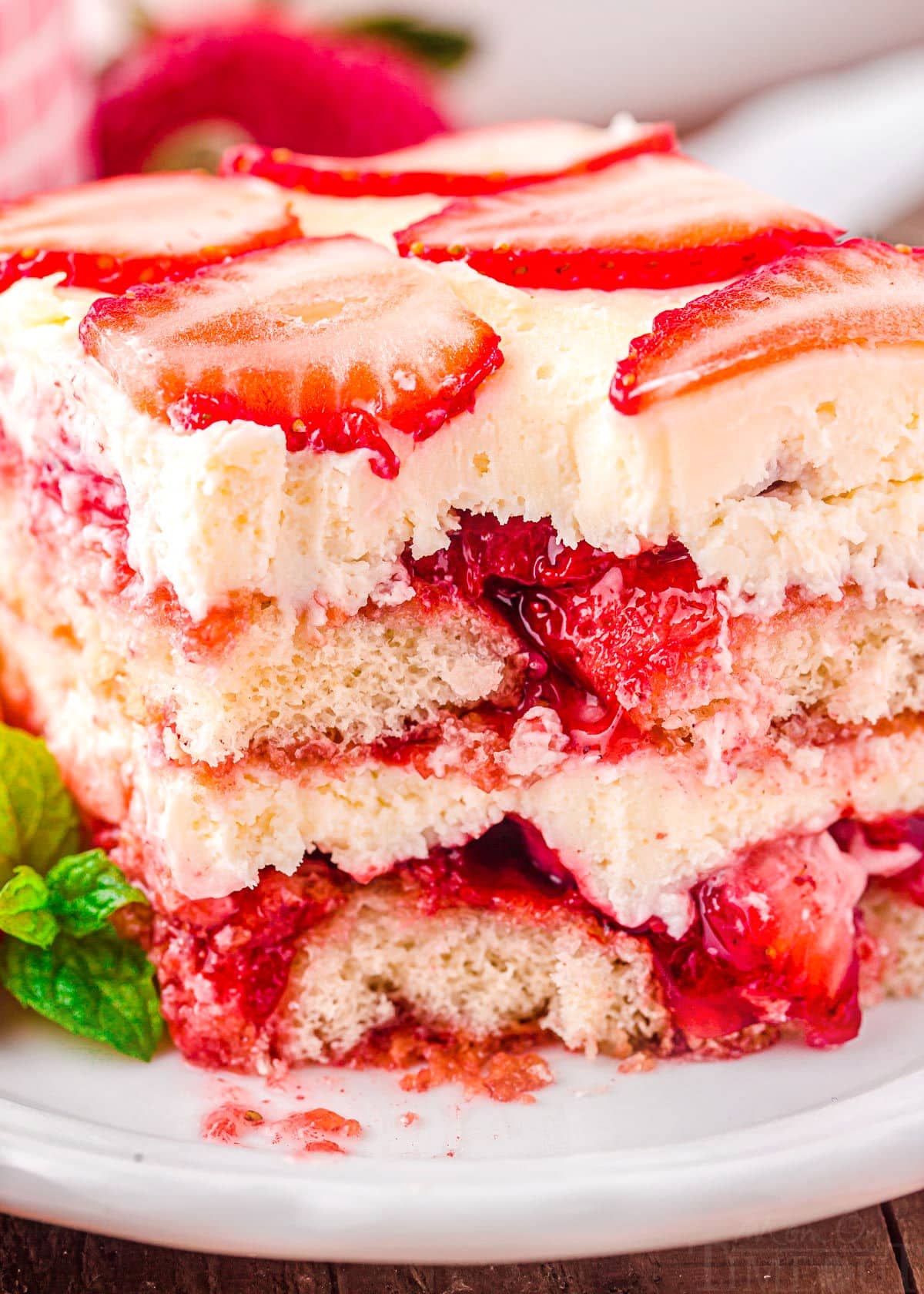 close up look at all of the layers in the strawberry tiramisu after a forkful has been removed.