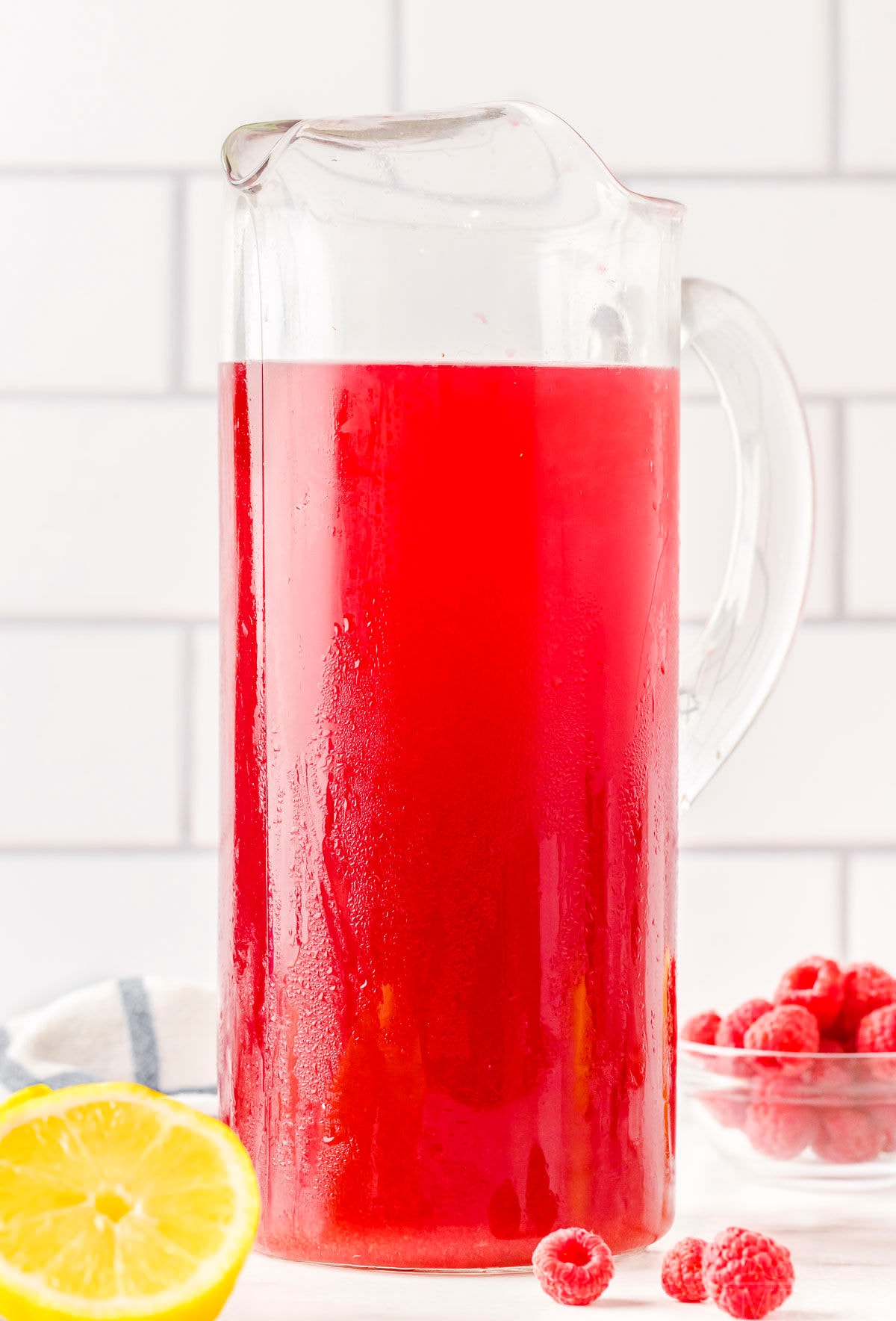 tall glass pitcher filled with raspberry iced tea ready to be enjoyed.