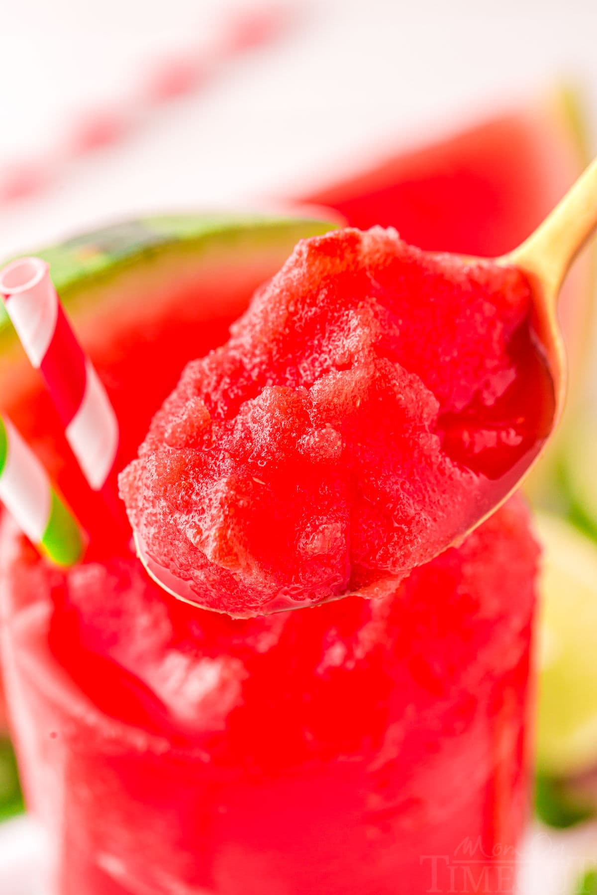 spoonful of watermelon slushy held above slushie glass.