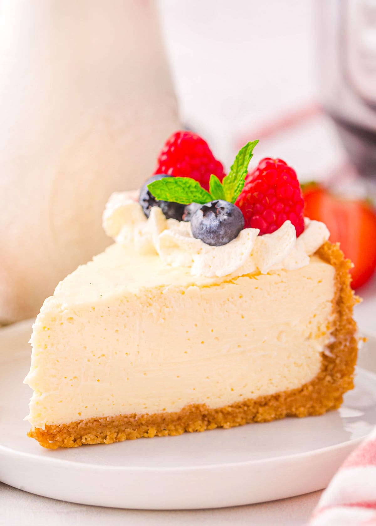 slice of cheesecake on white plate topped with whipped cream and berries.