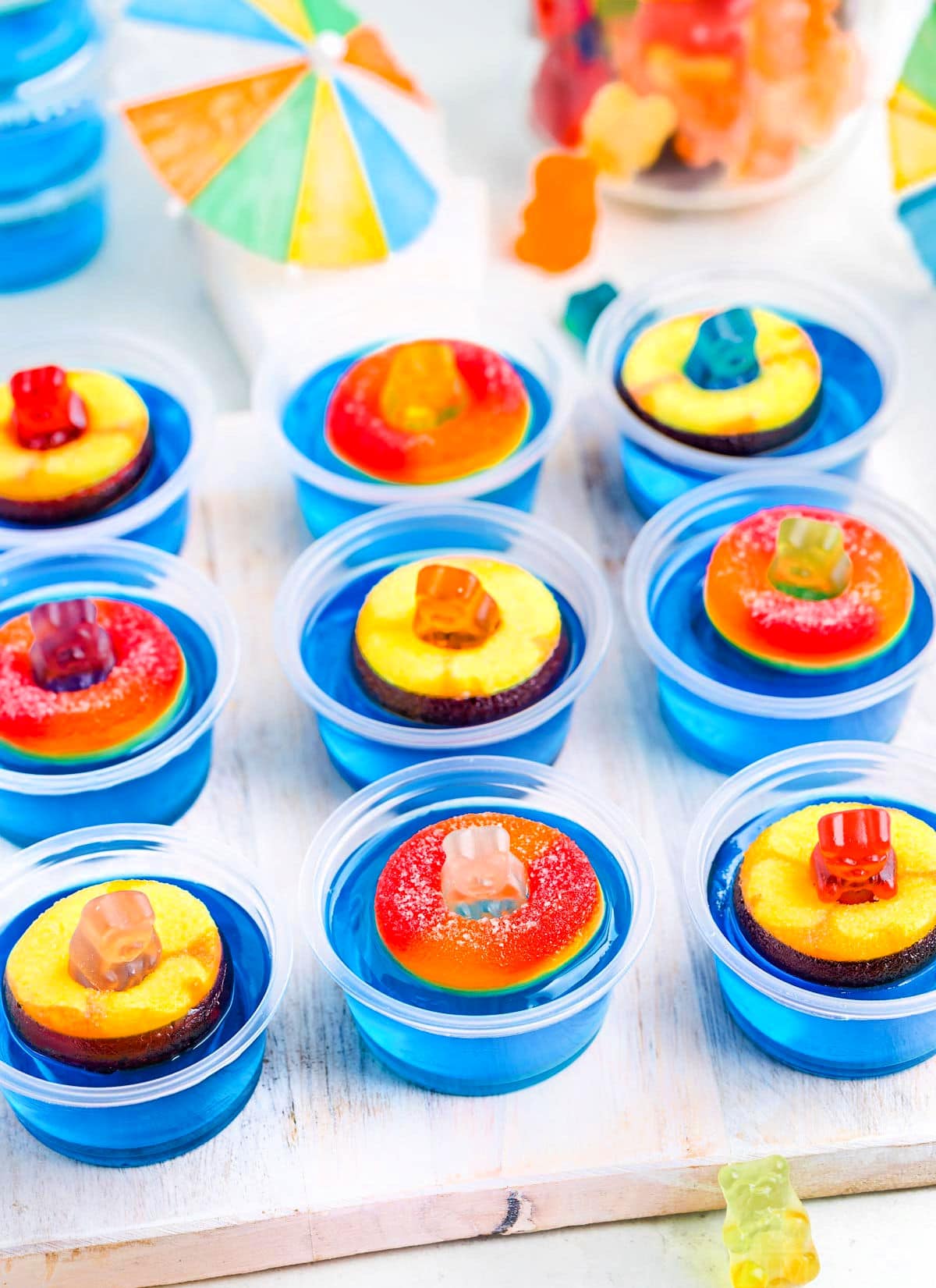 white tray topped with pool party jello shots. paper umbrellas and more gummy bears can be seen in the background.