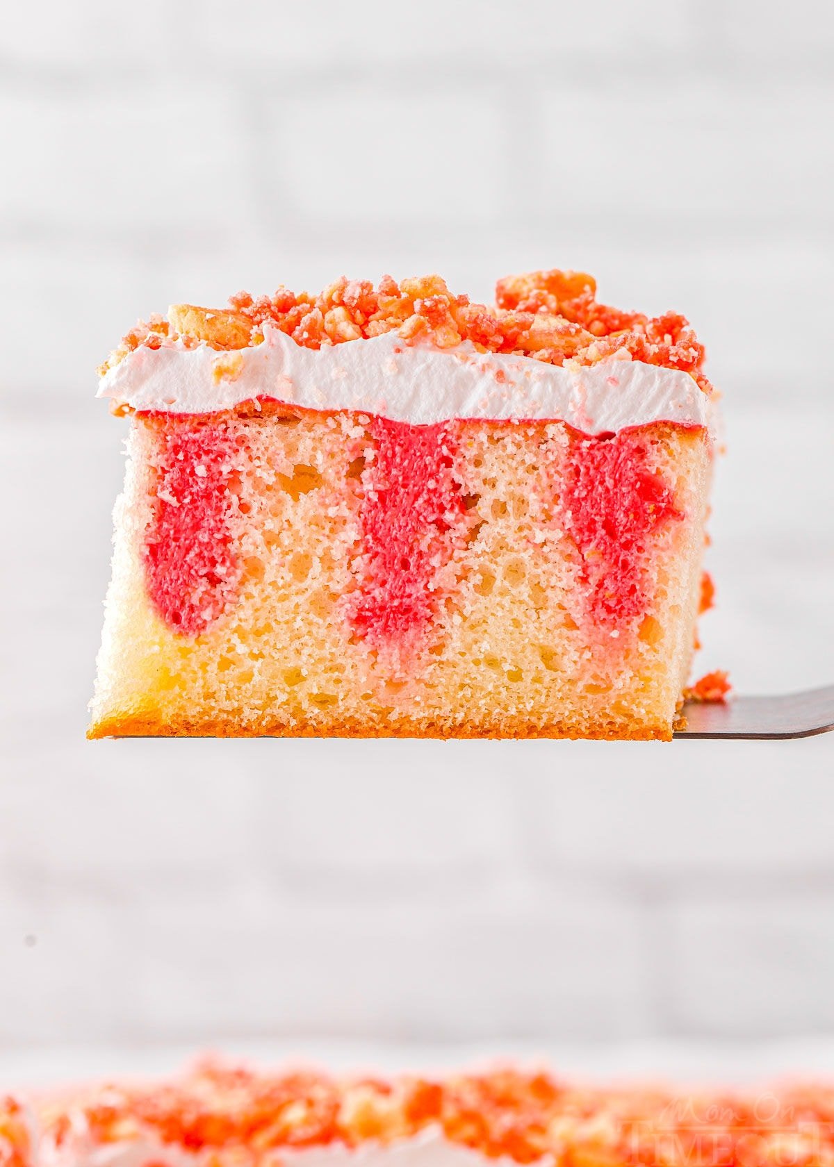 slice of strawberry poke cake recipe held up above the rest of the cake.