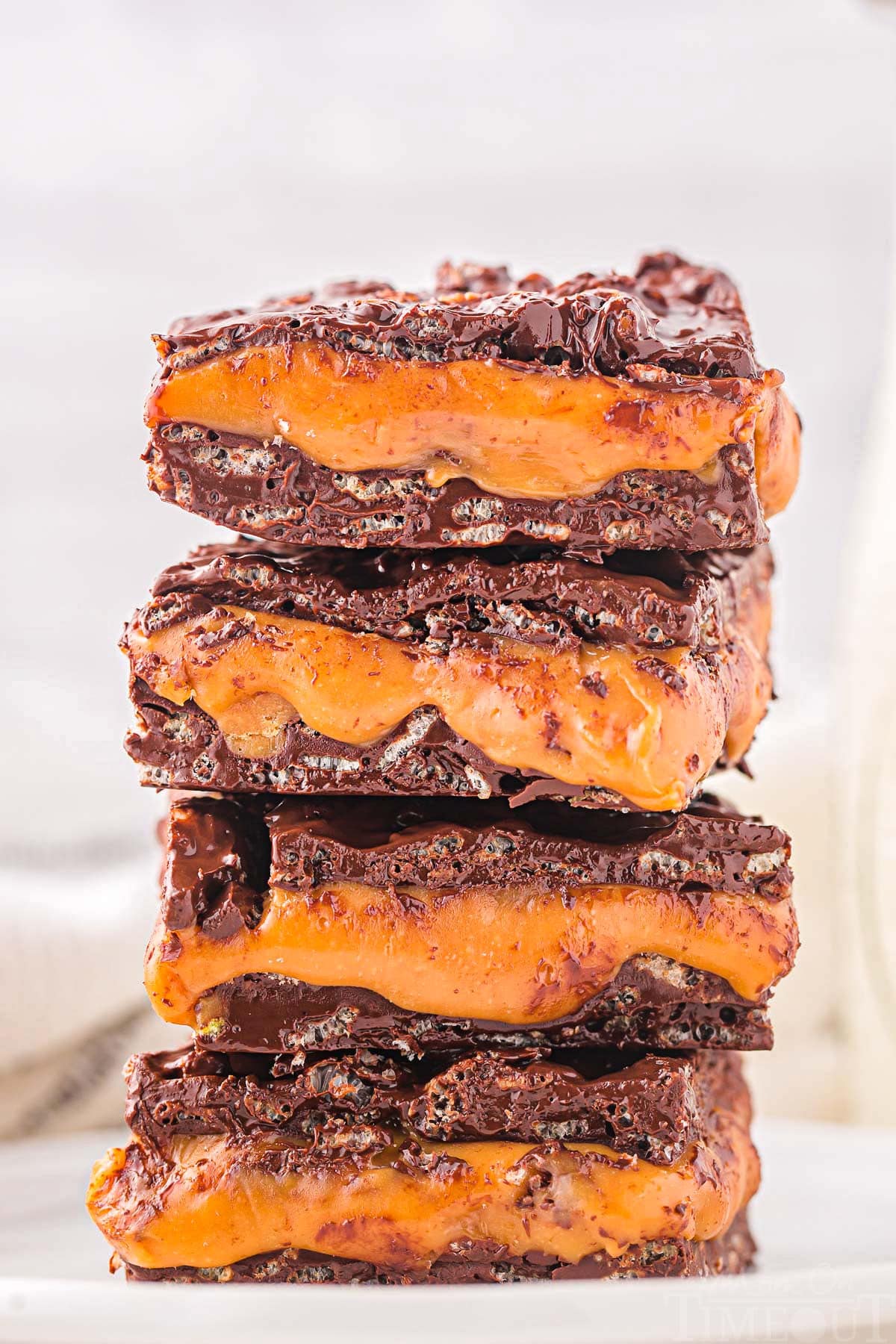 homemade 100 grand bar recipe cut into squares and stacked four high on a white plate.