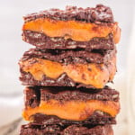 homemade 100 grand candy bars recipe cut into squares and stacked four high on a white plate.