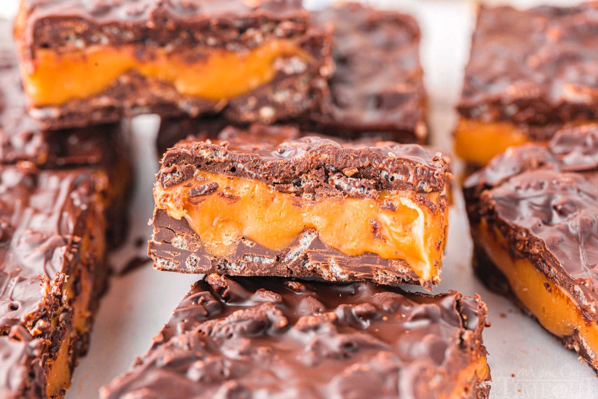 100 grand bars laid out on white surface with one bar tilted so you can see the thick caramel layer.