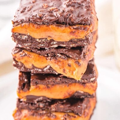 homemade 100 grand bar recipe cut into squares and stacked four high on a white plate.