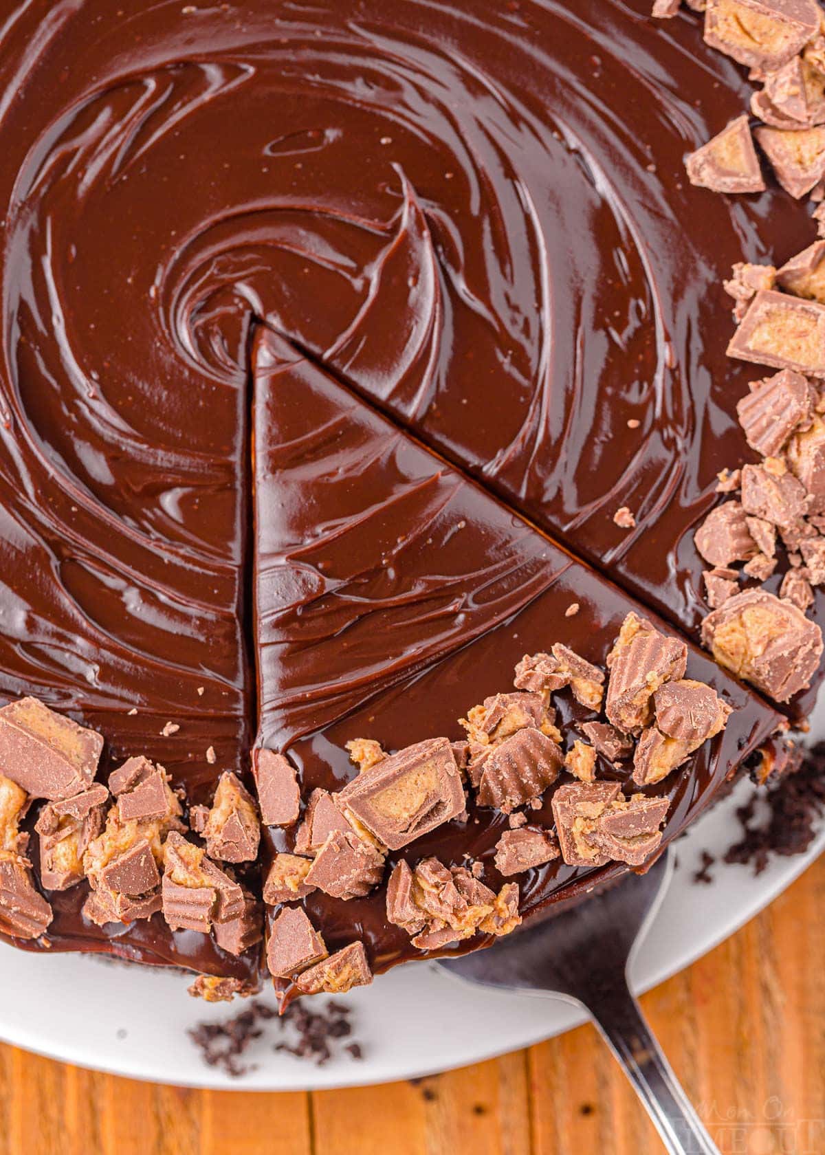 top down view of peanut butter cheesecake topped with chocolate ganache. One piece is being lifted away with a pie server.