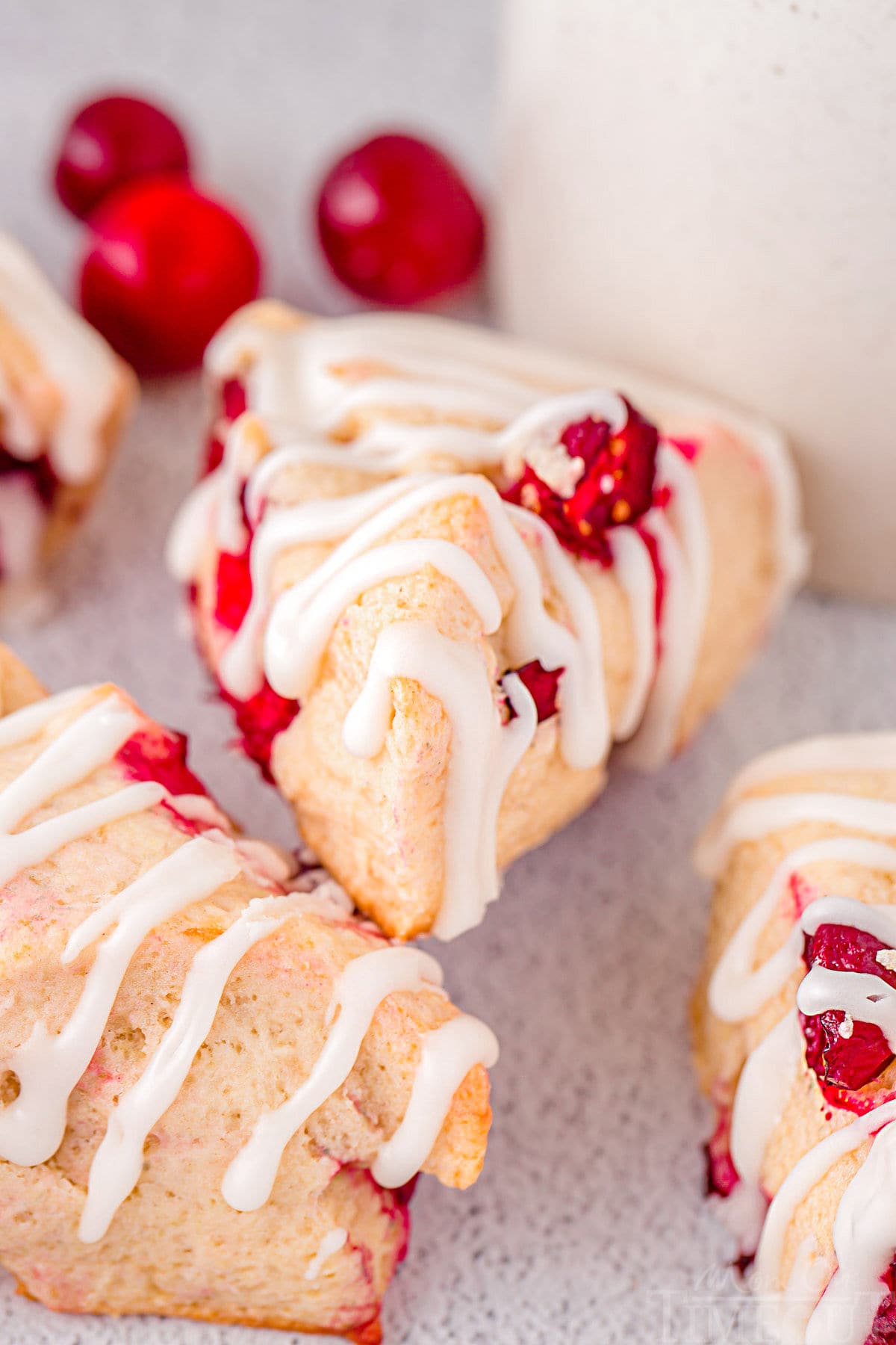 easy cranberry scones with glaze sitting on white surface with fresh cranberries scattered about.