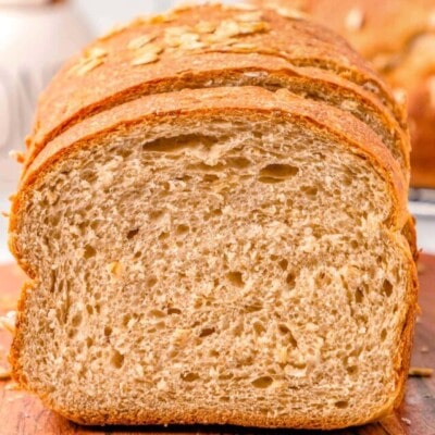 loaf of whole wheat board on a wood board with the end cut off.