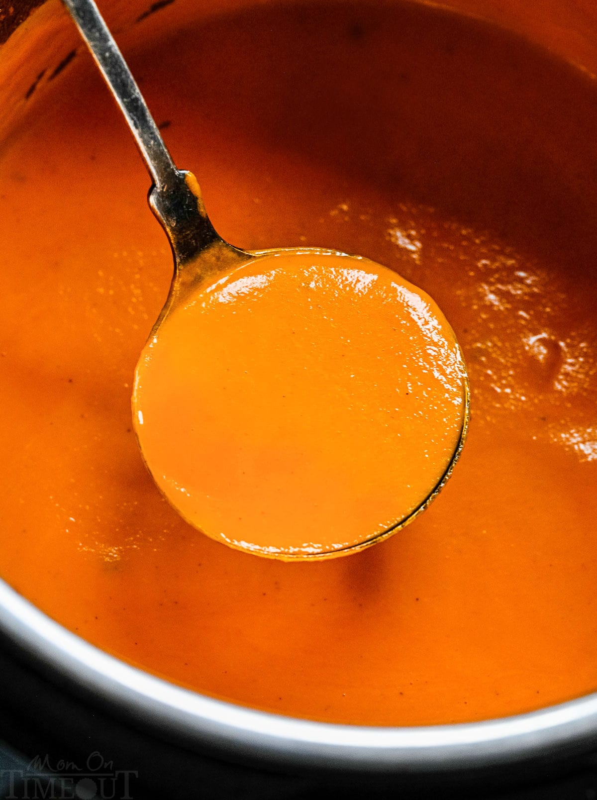 instant pot filled with tomato soup and a ladle lifting out a ladle full of the soup.