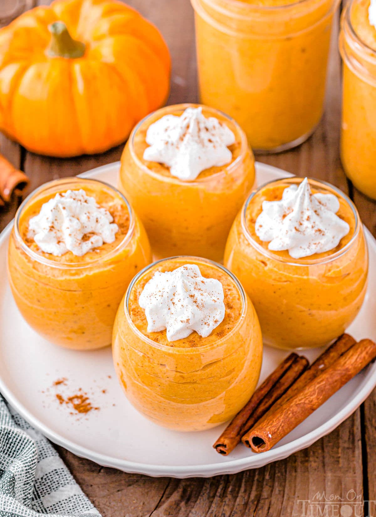 top down angled view of four glasses filled with pumpkin mousse topped with whipped cream.