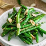 small round white plate with a serving of garlic green beans on it.