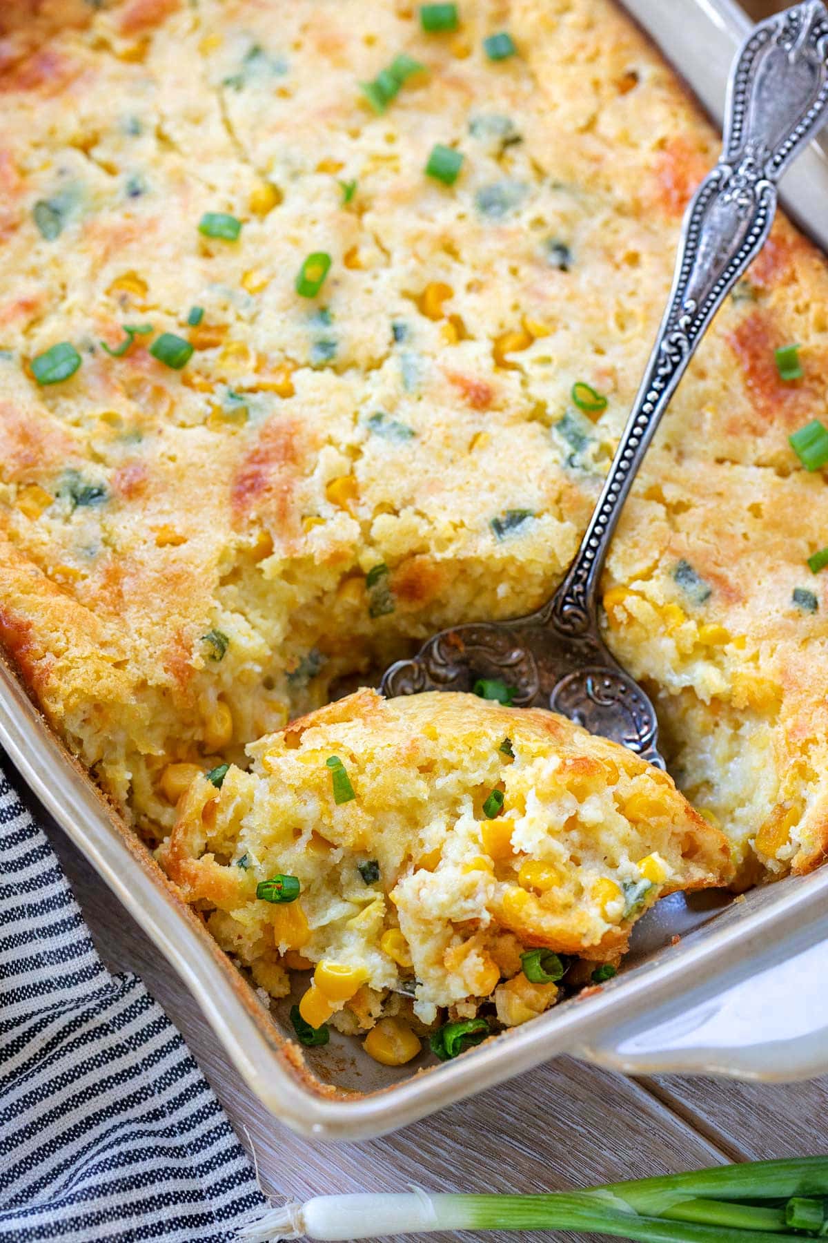 scoop of creamy corn casserole being taken out of the baking dish.