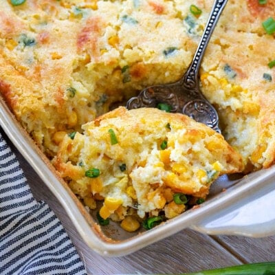 scoop of creamy corn casserole being taken out of the baking dish.