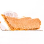 slice of no bake pumpkin pie held above pie plate.