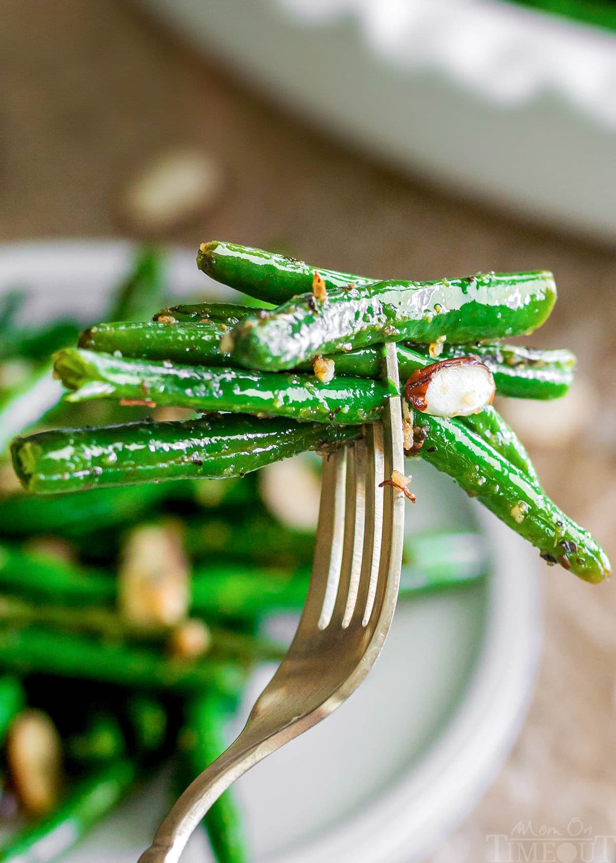forkful of garlic green beans held over a plate.