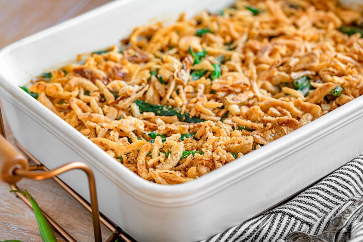 side view of the green bean casserole recipe topped with fried onions in a large white casserole dish.
