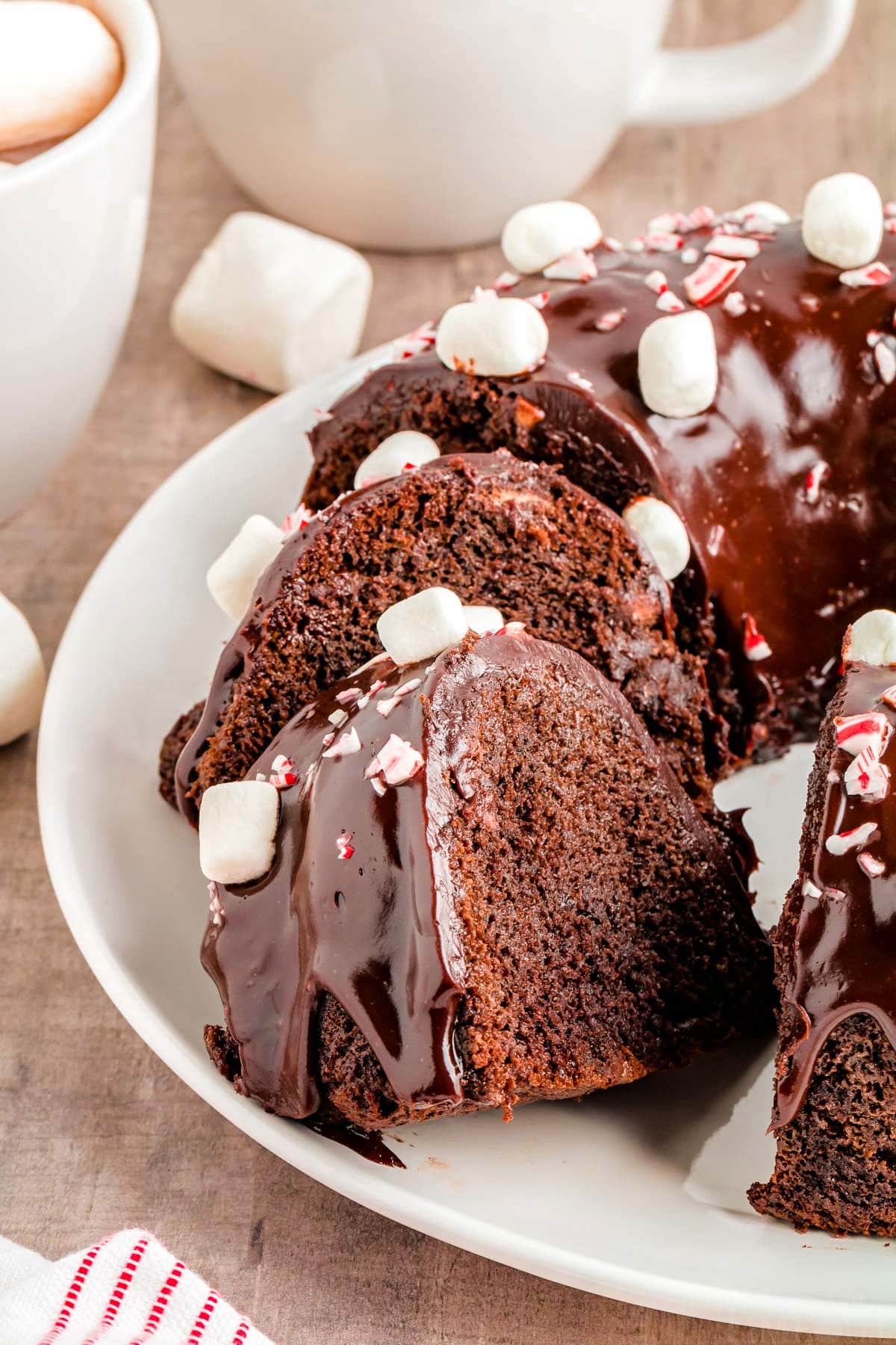 chocolate peppermint bundt cake on white plate with two slices cut out and sat an angle.