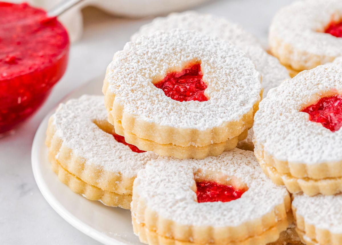 linzer cookie recipe assembled with raspberry jam filling and topped with powdered sugar.