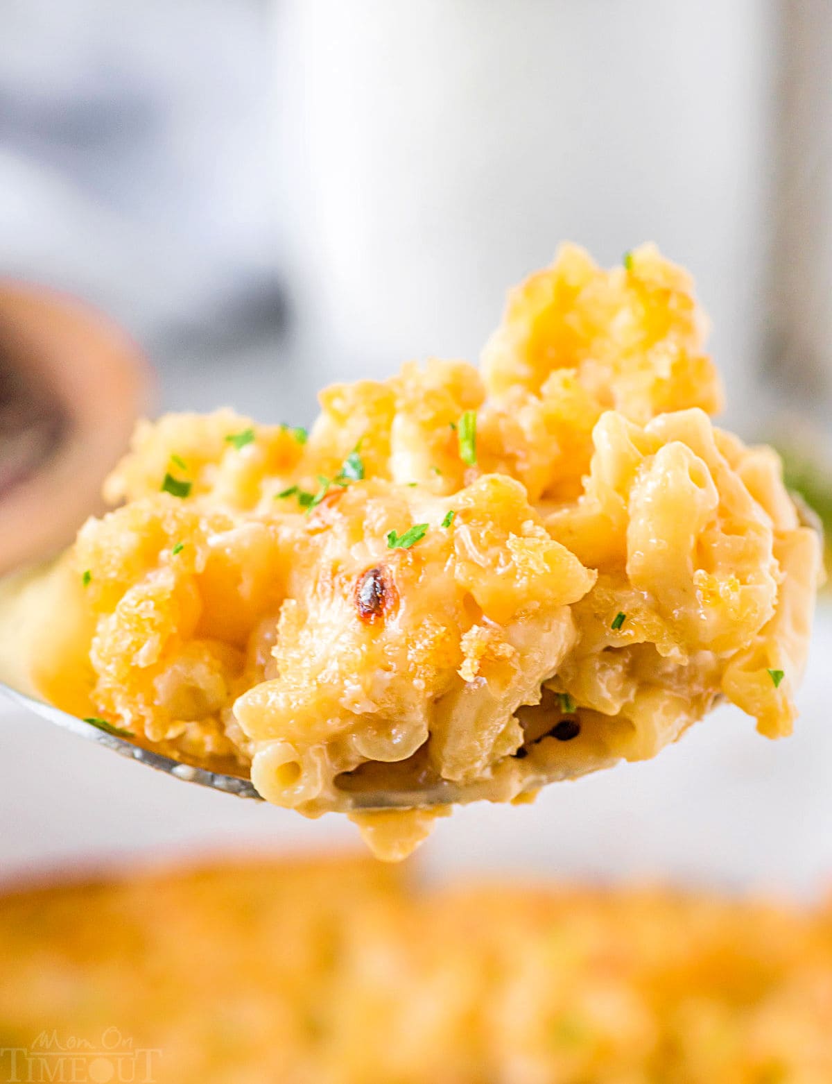 large spoon full of creamy velveeta mac and cheese held above the casserole dish.