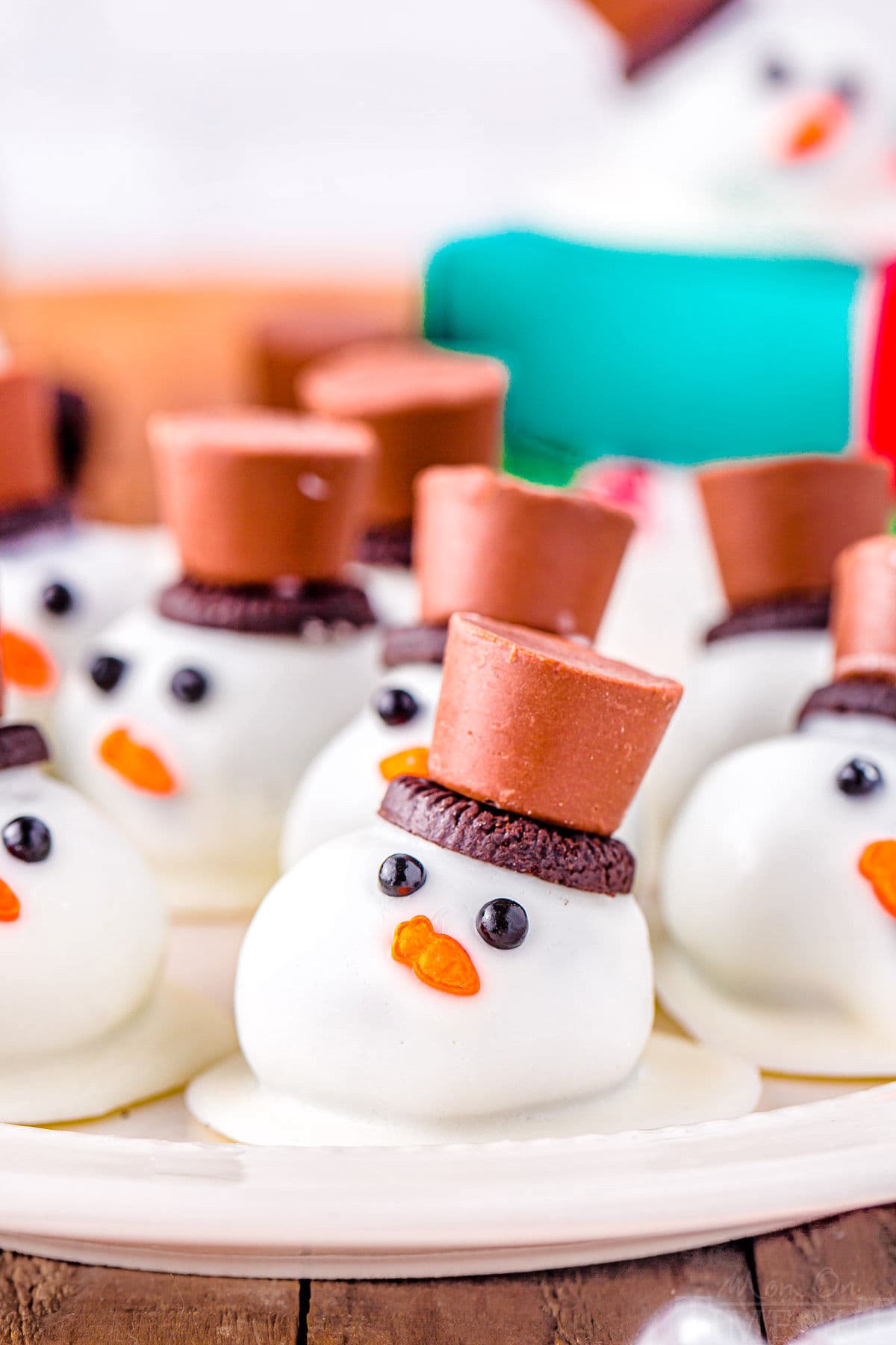 melting snowman oreo balls on a white plate topped with mini oreos and rolo candy. 