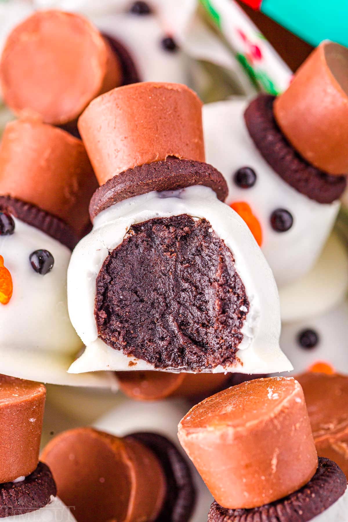 snowman oreo ball with a bite taken out of it in a box with more melting snowman. 