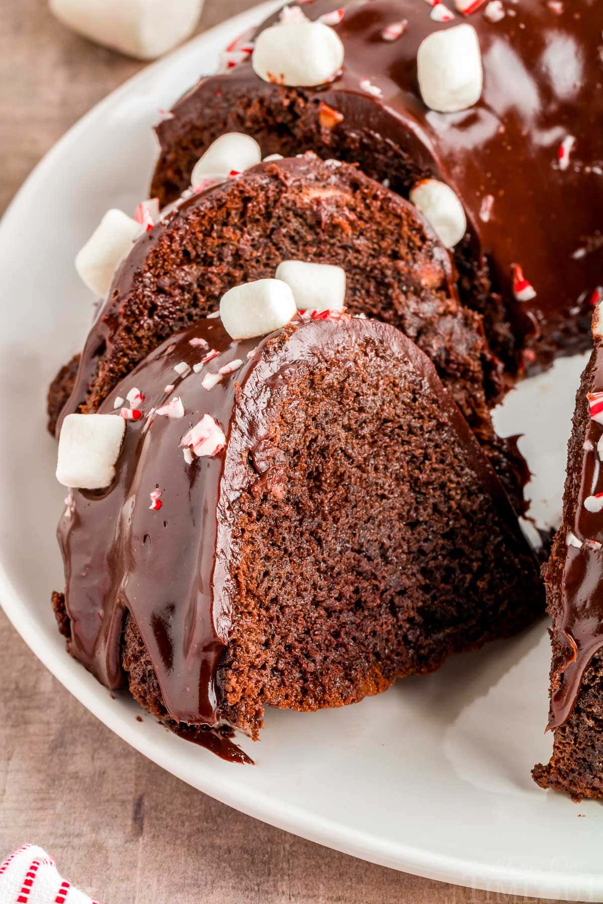 chocolate peppermint bundt cake on white plate with two slices cut out and sat an angle.