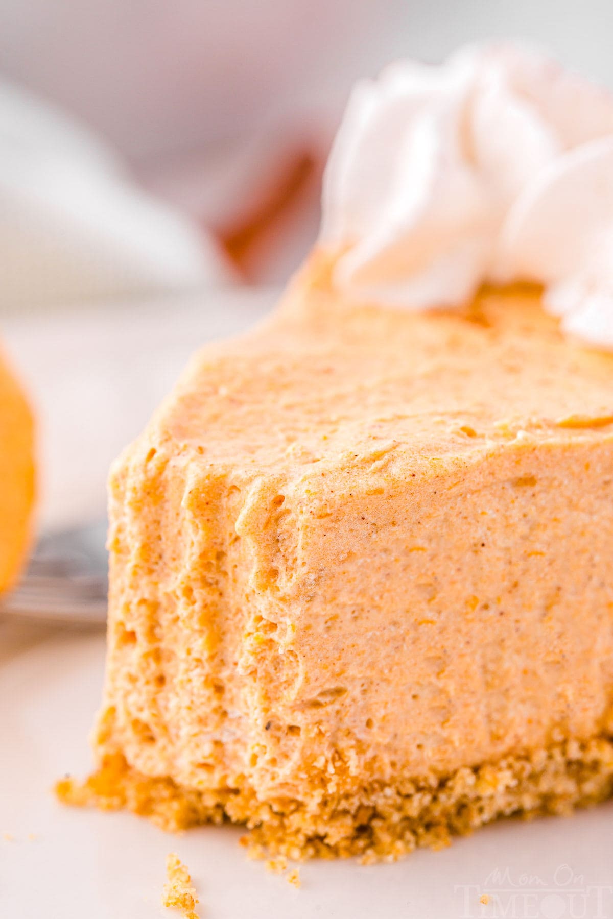 close up look at slice of no bake pumpkin pie with a bite taken. the fork tines are clearly seen in the soft filing.