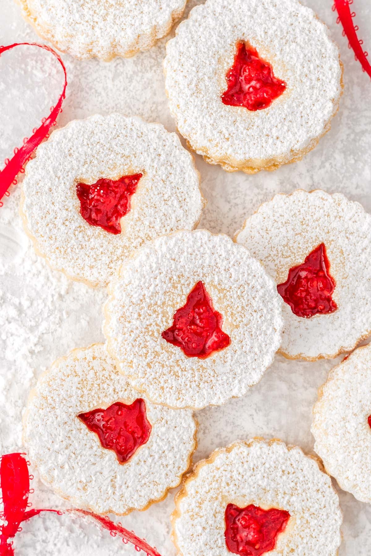 top down look at linzer cookies dusted with  powdered sugar and a raspberry jam filling.