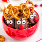 red bowl filled with reindeer pretzels with red candy noses and pretzel antlers.