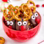 red bowl filled with reindeer pretzels with red candy noses and pretzel antlers.