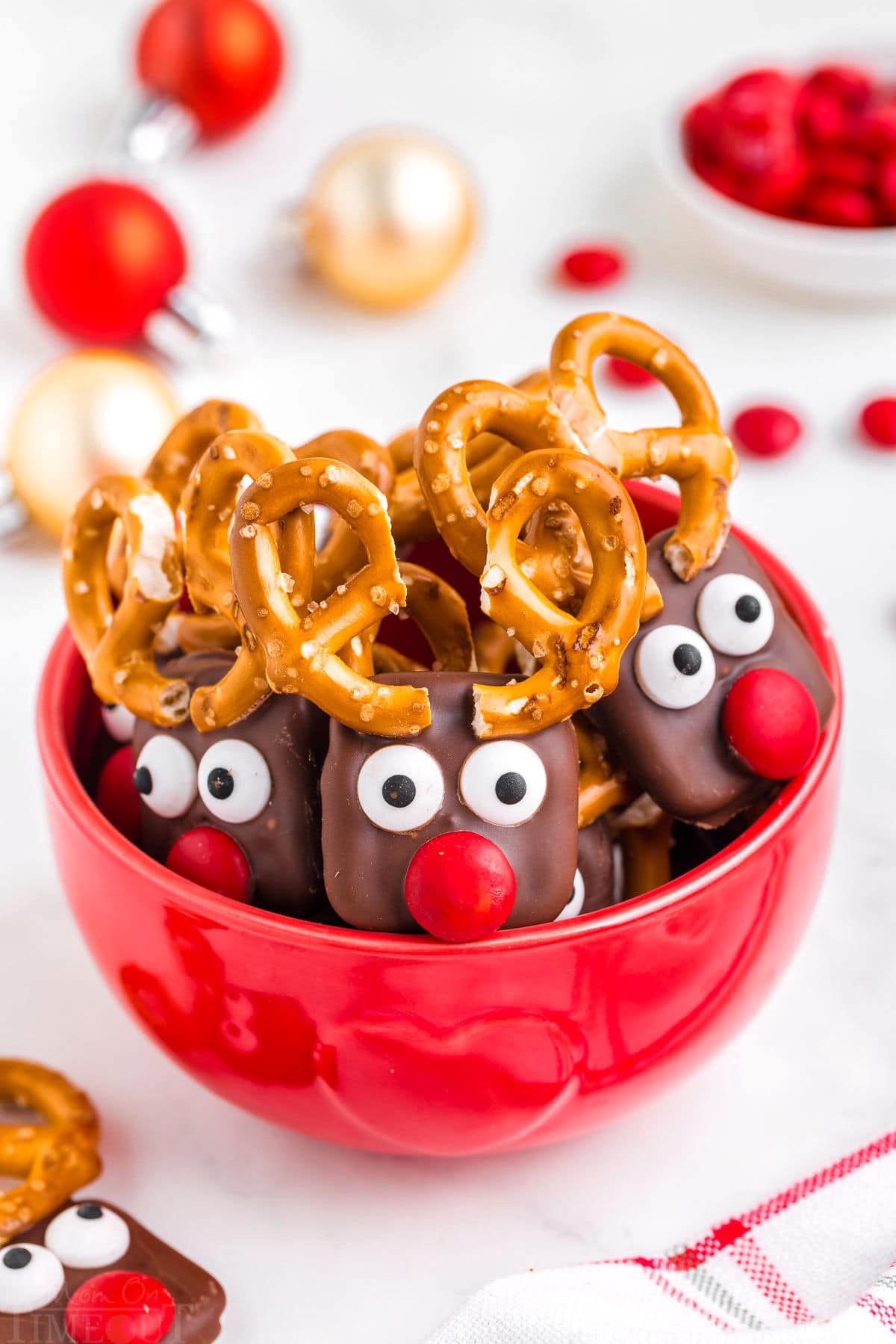 red bowl filled with reindeer pretzels with red candy noses and pretzel antlers.