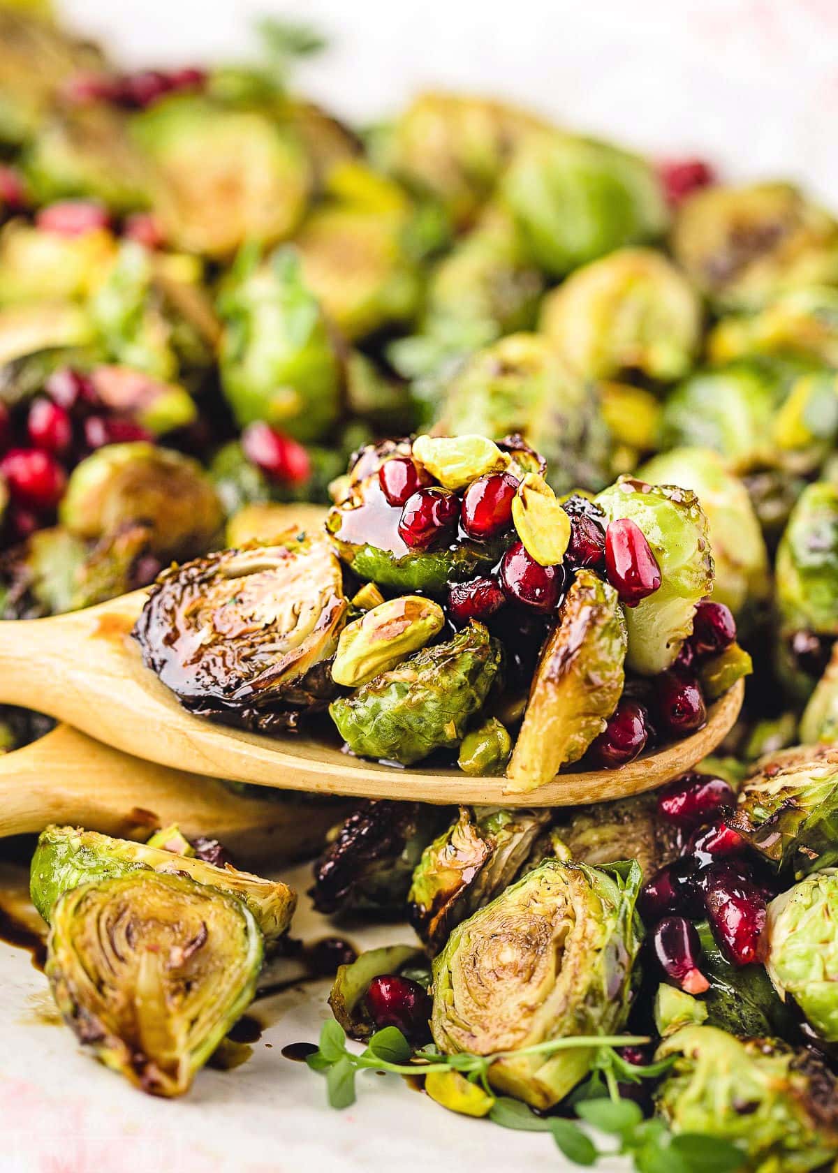 wooden spoon with roasted brussels sprouts sitting on more sprouts.