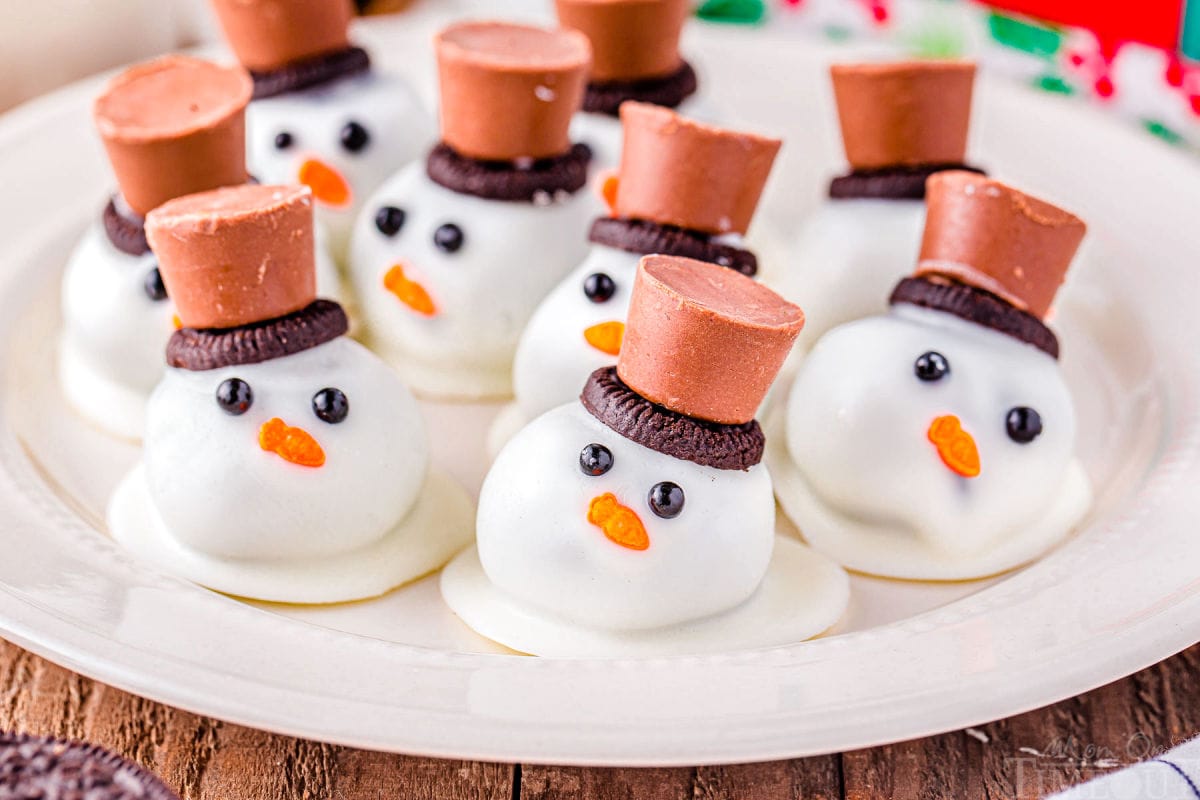melting snowman oreo balls on a white plate topped with mini oreos and rolo candy.