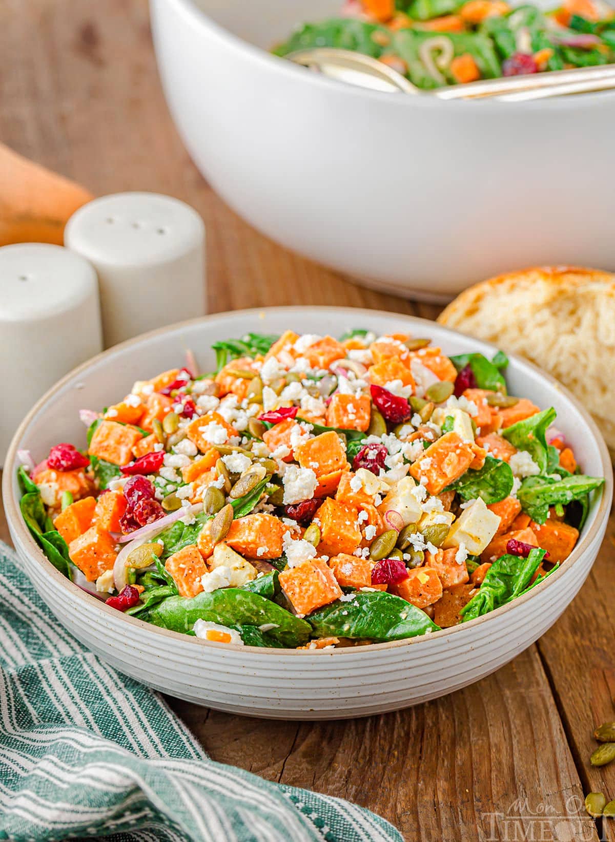large bowl of sweet potato salad topped with roasted cubed sweet potatoes, dried cranberries, pepitas and feta cheese.
