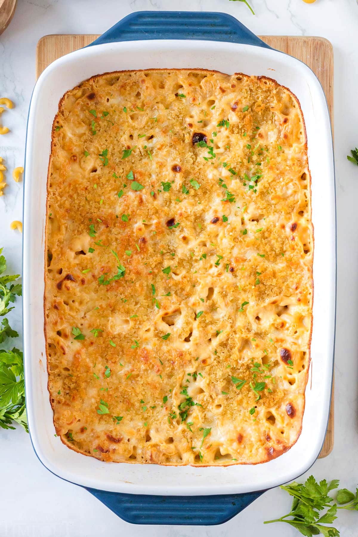 top down look at velveeta mac and cheese in a casserole dish topped with fresh parsley.