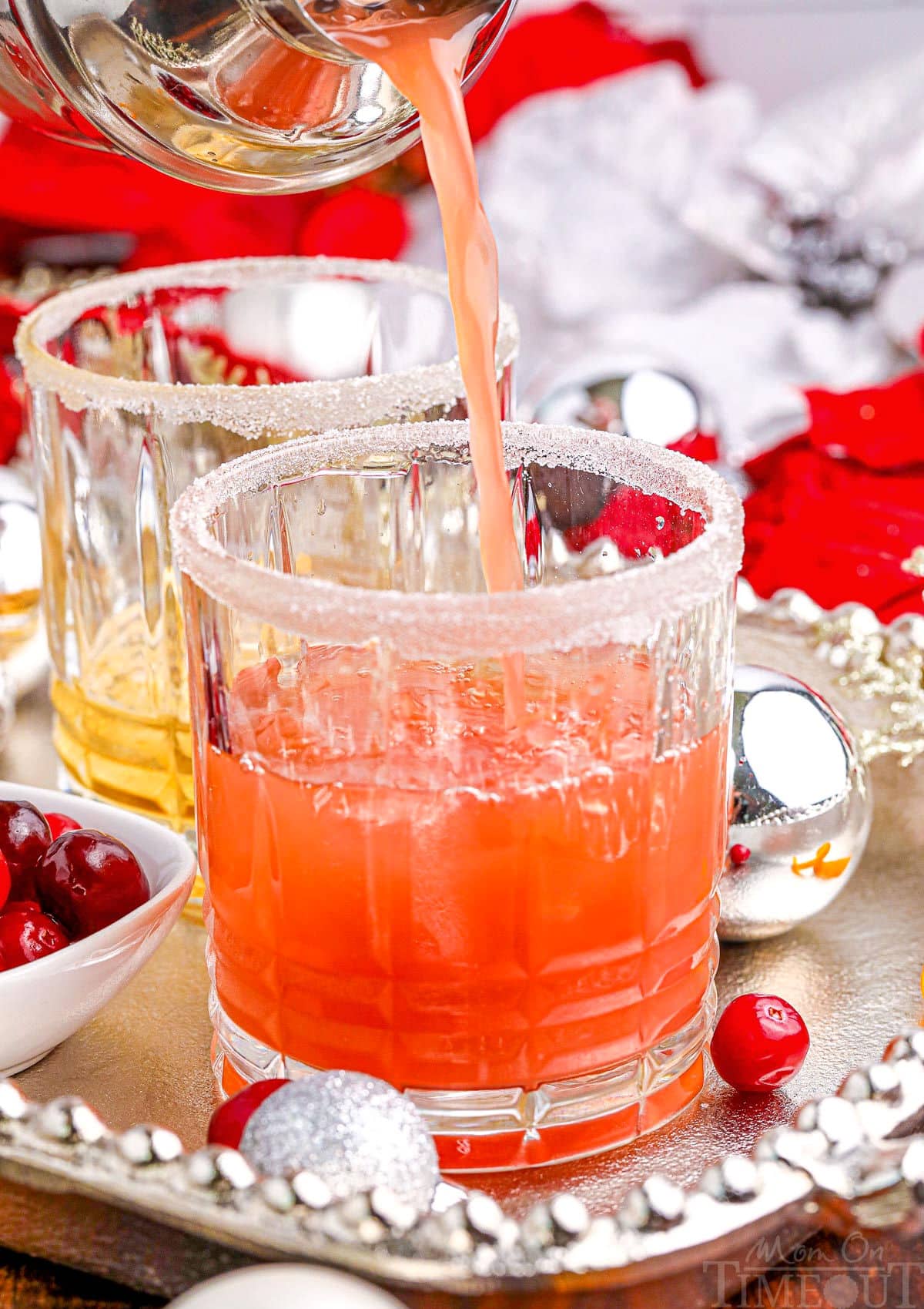 christmas cocktail being poured into short crystal glass sitting on silver tray.