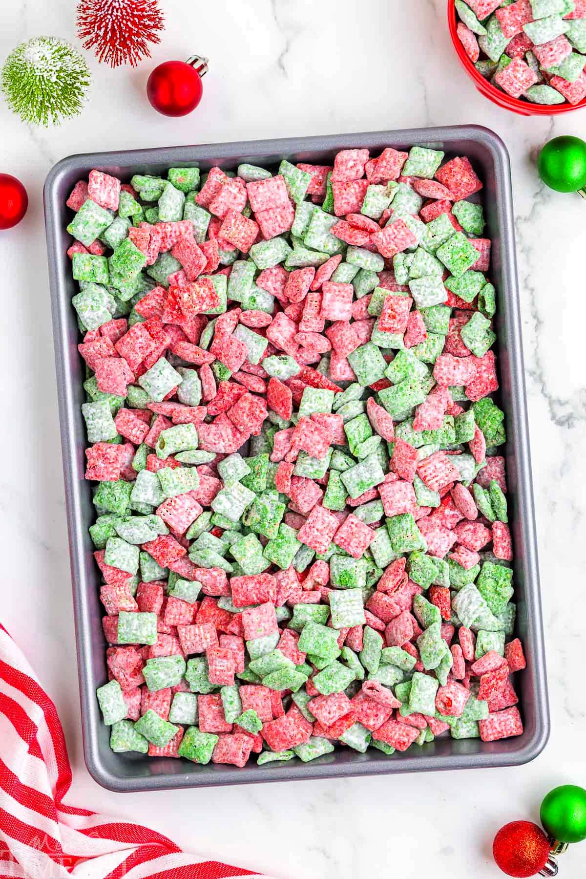 top down look at christmas muddy buddies recipe spread out on a sheet pan.