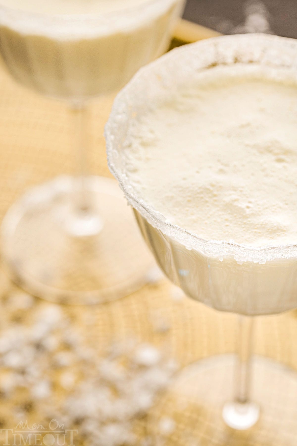 angled top down view of white martini in tall glass dusted with sugar for a snowy look.