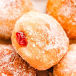 close up look at jelly filled donut rolled in sugar sitting on a layer of more jelly donuts.