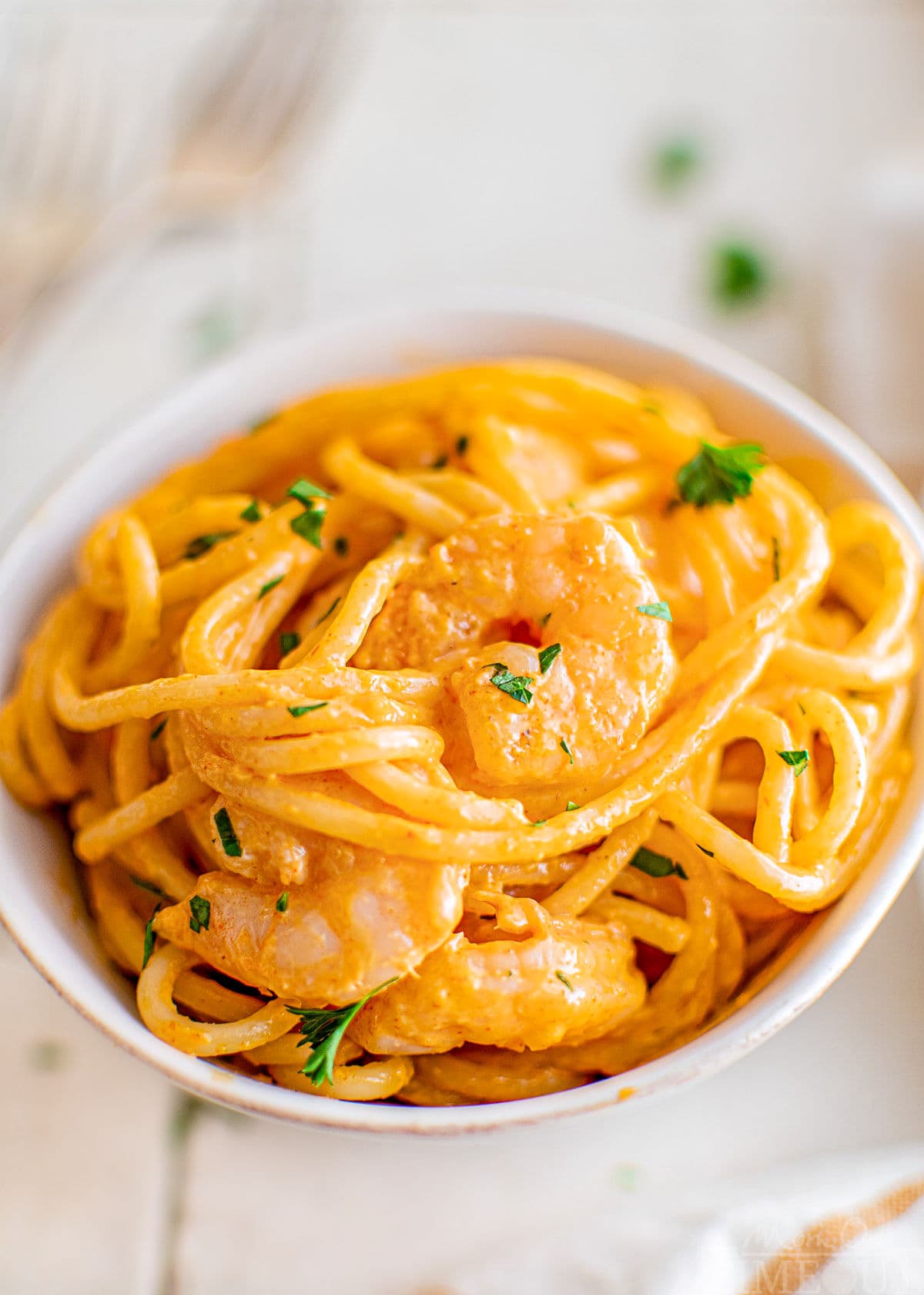 small bowl with bang bang shrimp pasta in it. the bowl is white and the pasta is garnished with fresh parsley.