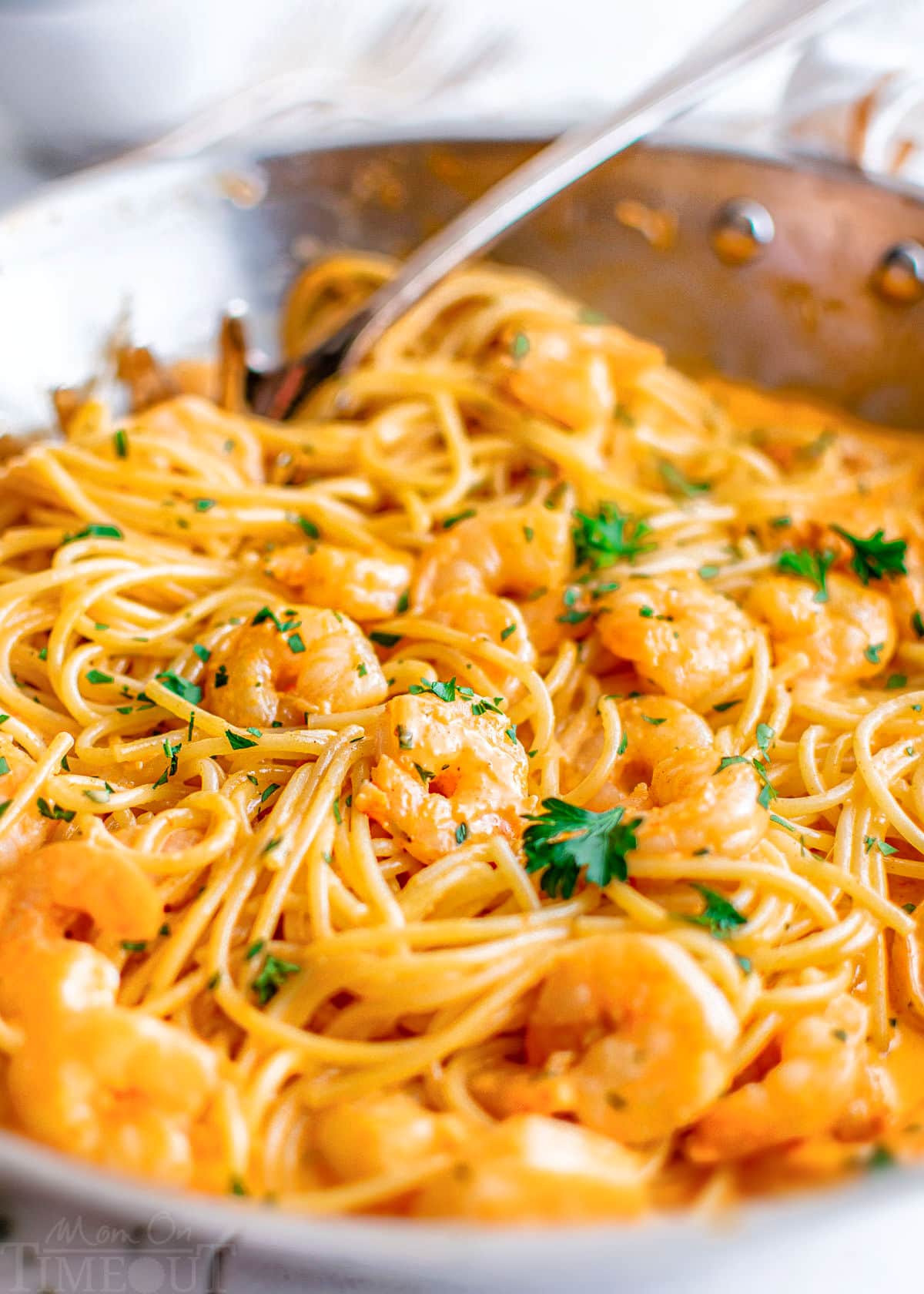 close up of bang bang shrimp pasta in a large stainless steel skillet topped with fresh parsley.