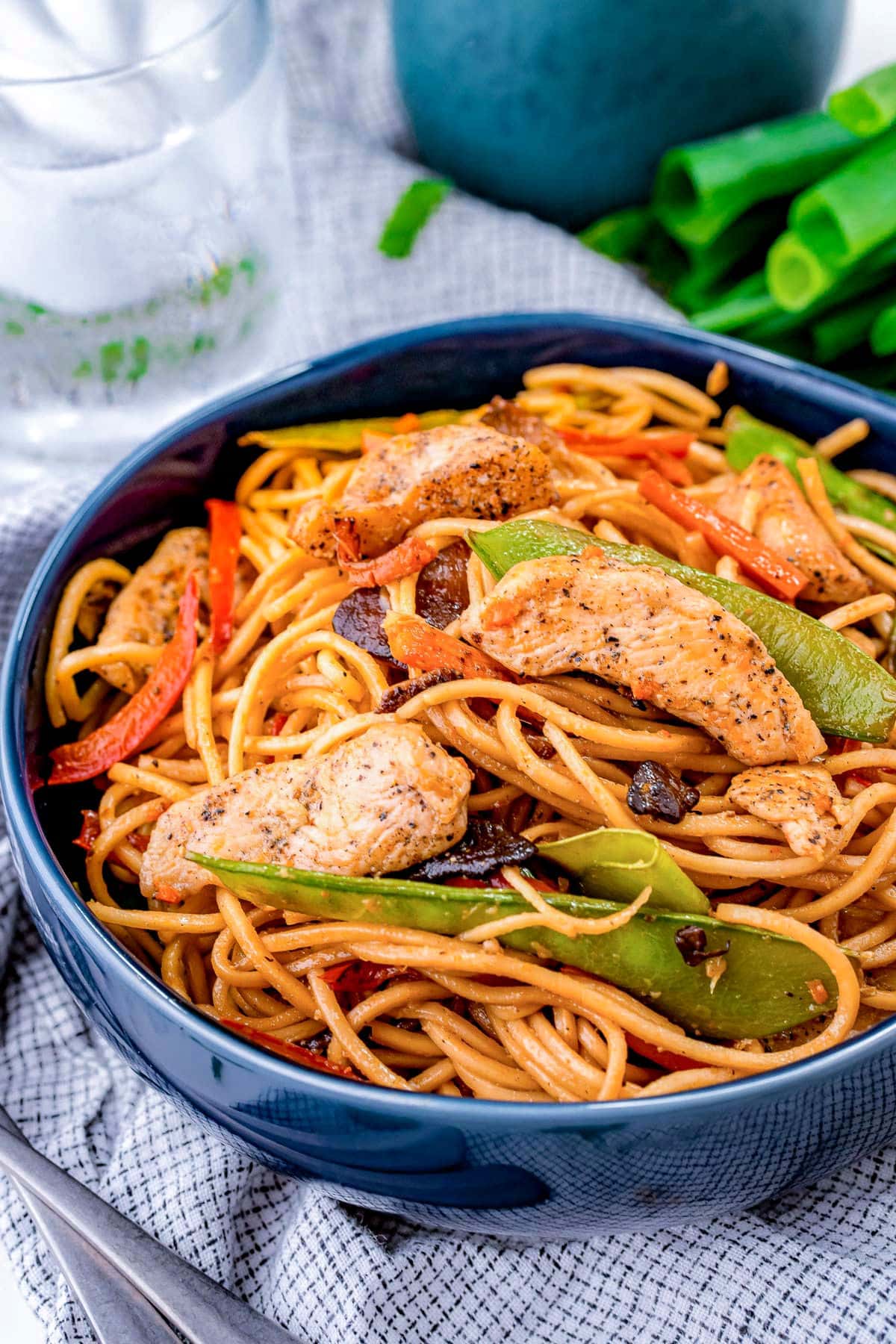 blue bowl filled with a generous serving of chicken lo mein made with snow peas and carrots.