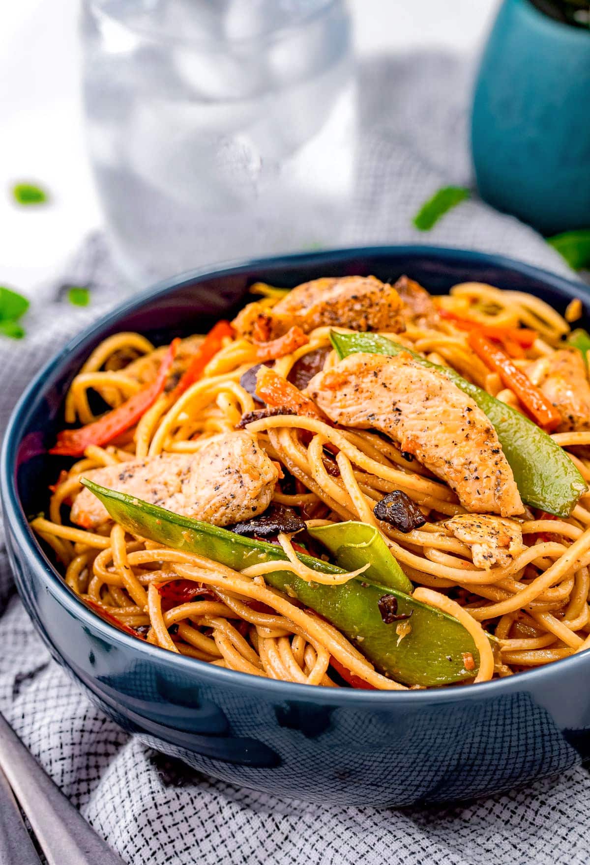 blue bowl filled with a generous serving of chicken lo mein made with snow peas and carrots.