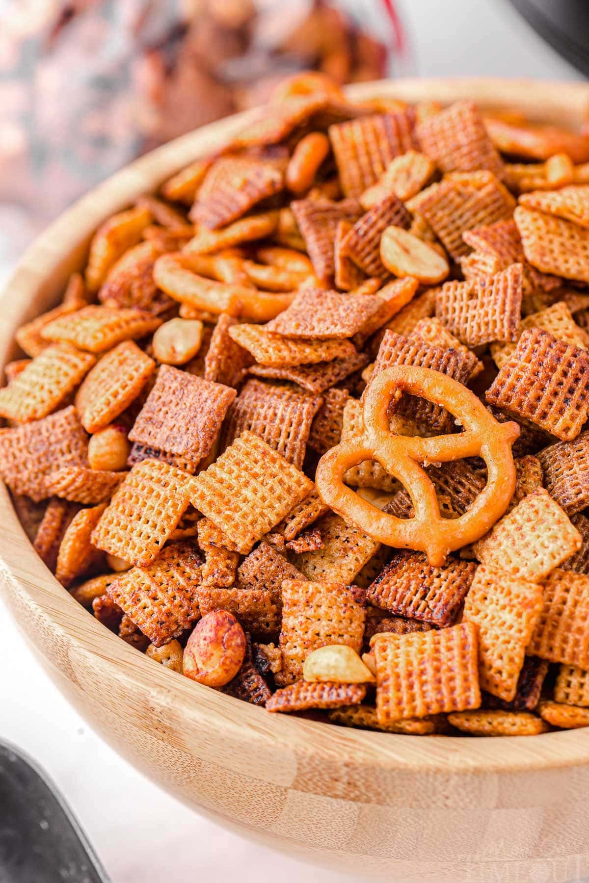 close up look at slow cooker chex mix in a large wood bowl.