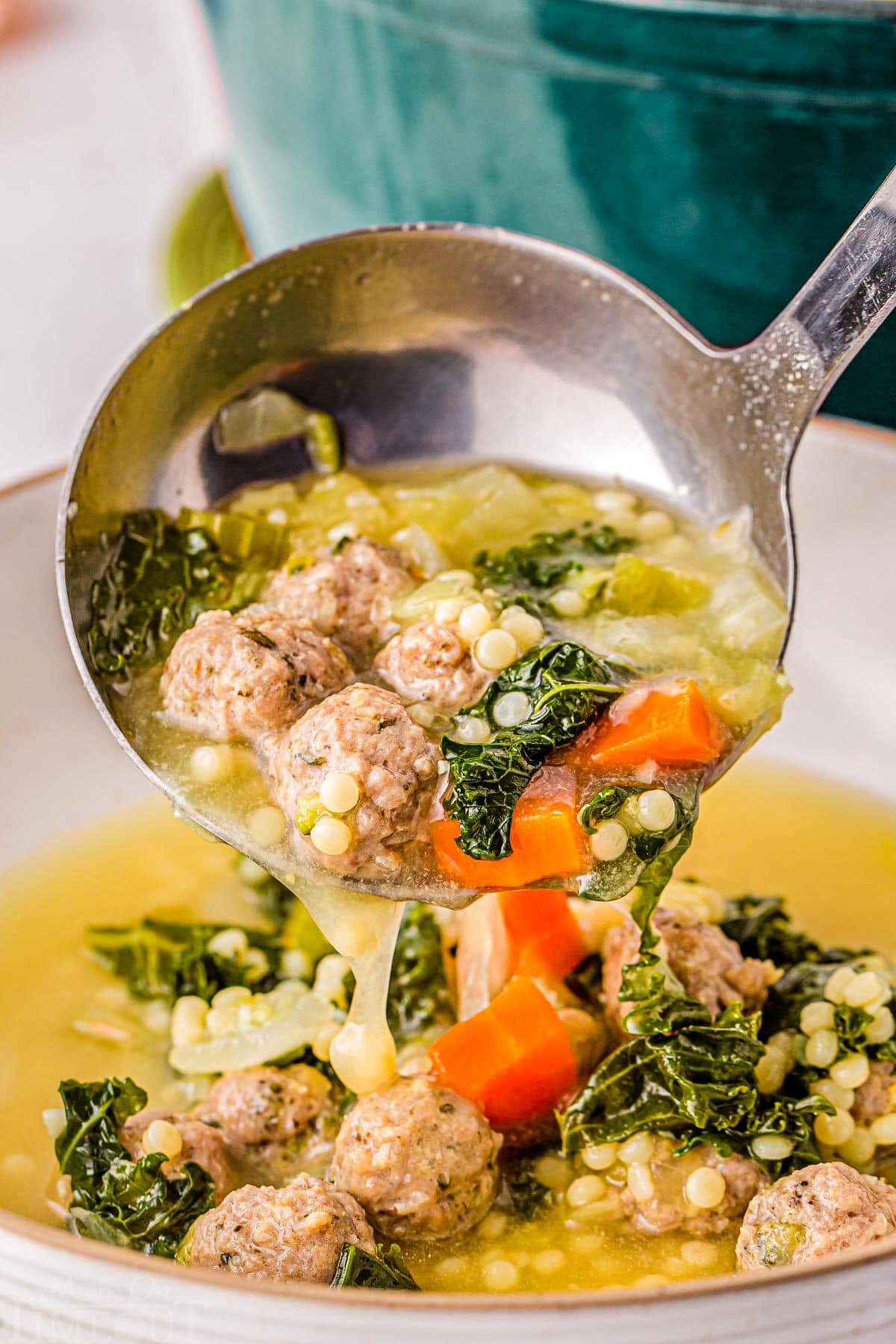 Ladle of Italian Wedding Soup being ladled into a big bowl.