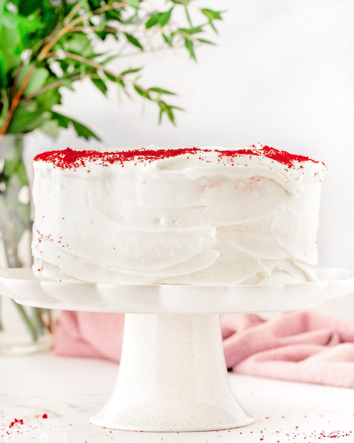 whole red velvet cake on a white pedestal cake stand.