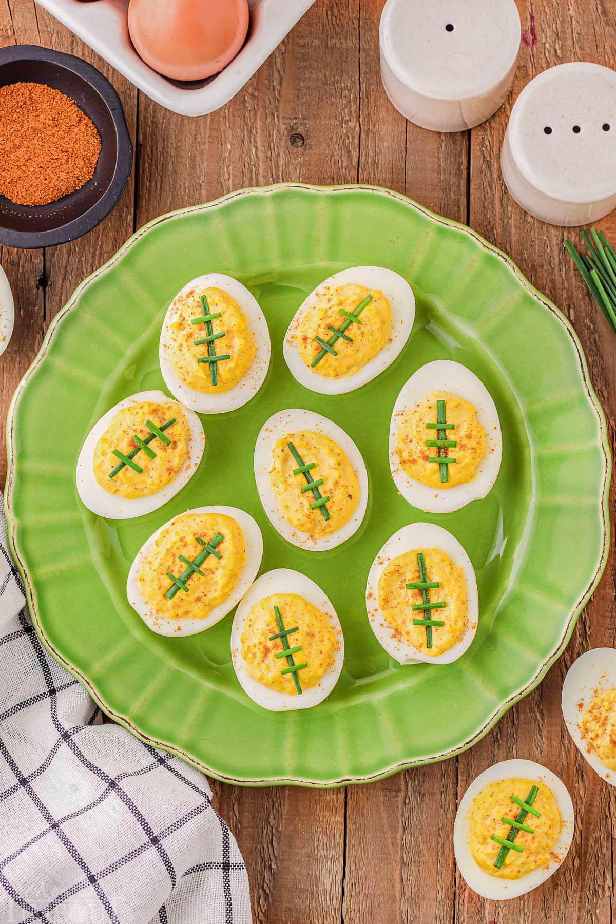 top down look at green plated loaded with deviled eggs that look like footballs.