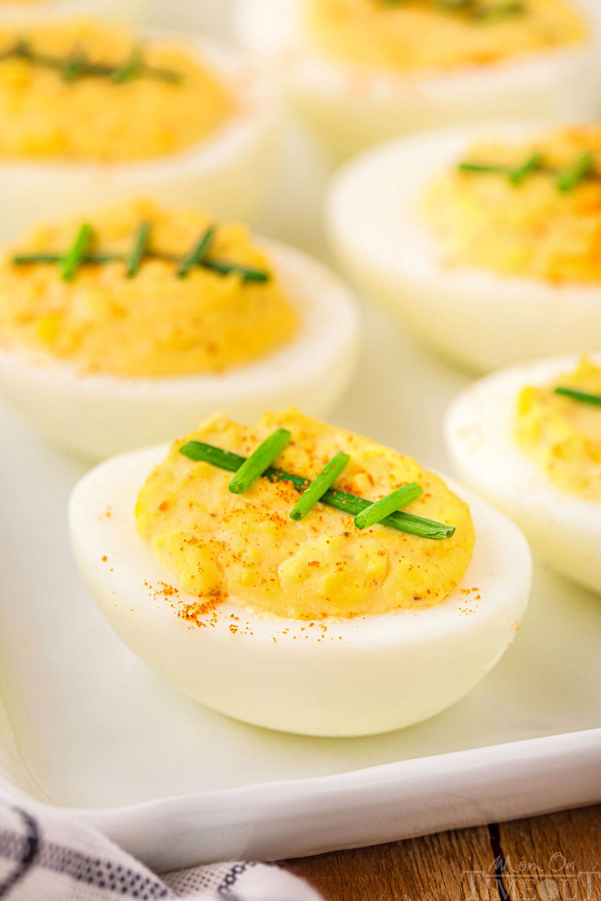 white plate of deviled eggs topped with chives. ready for a football party.