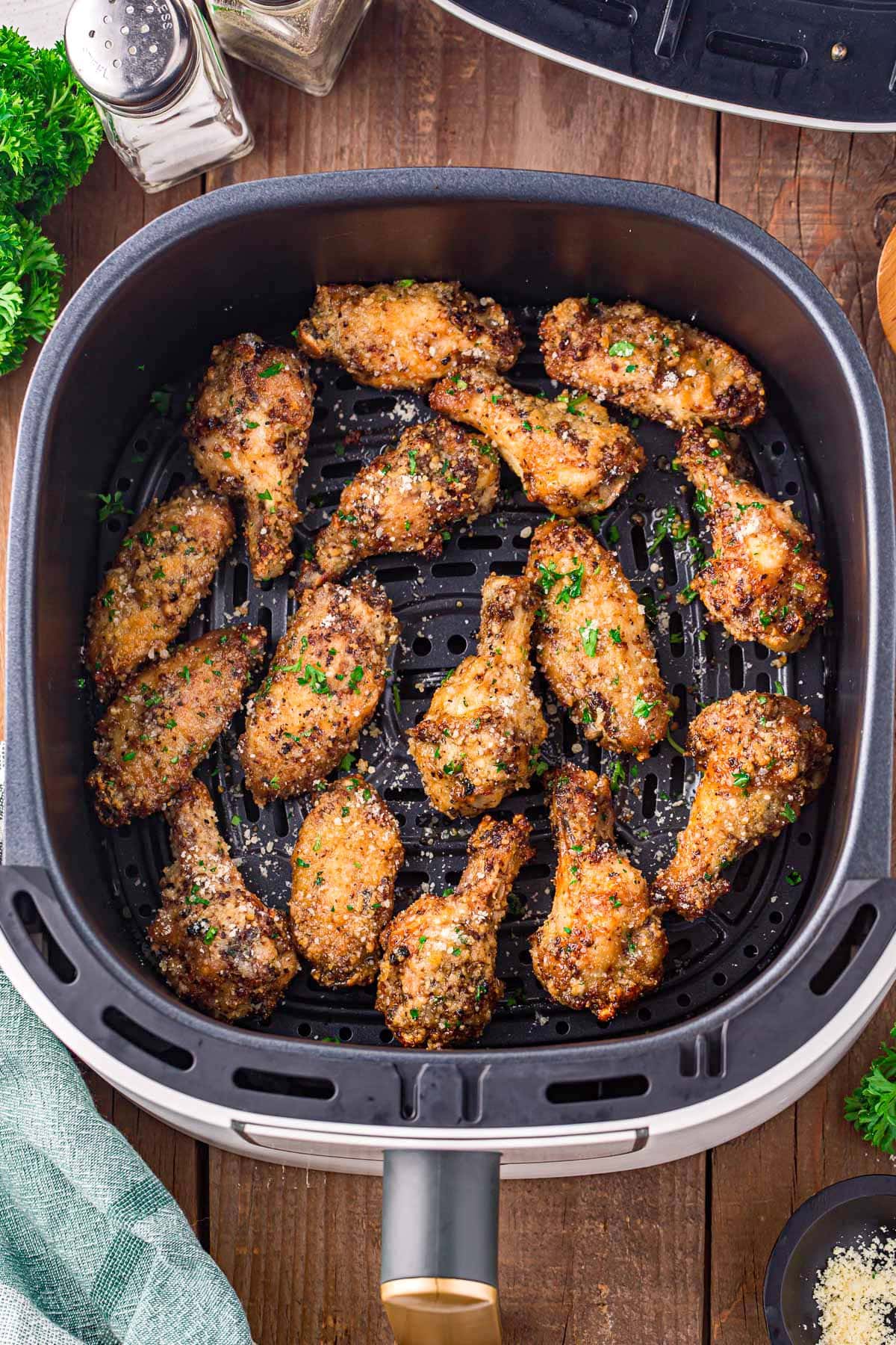 garlic parmesan wings in air fryer basket ready to be eaten.